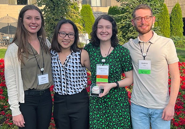 Photo of Don Warner's research group at INBRE '22. From left to right Alexia Caposio, Ashley Tran, Cat Merrill, and Andrea Feci.