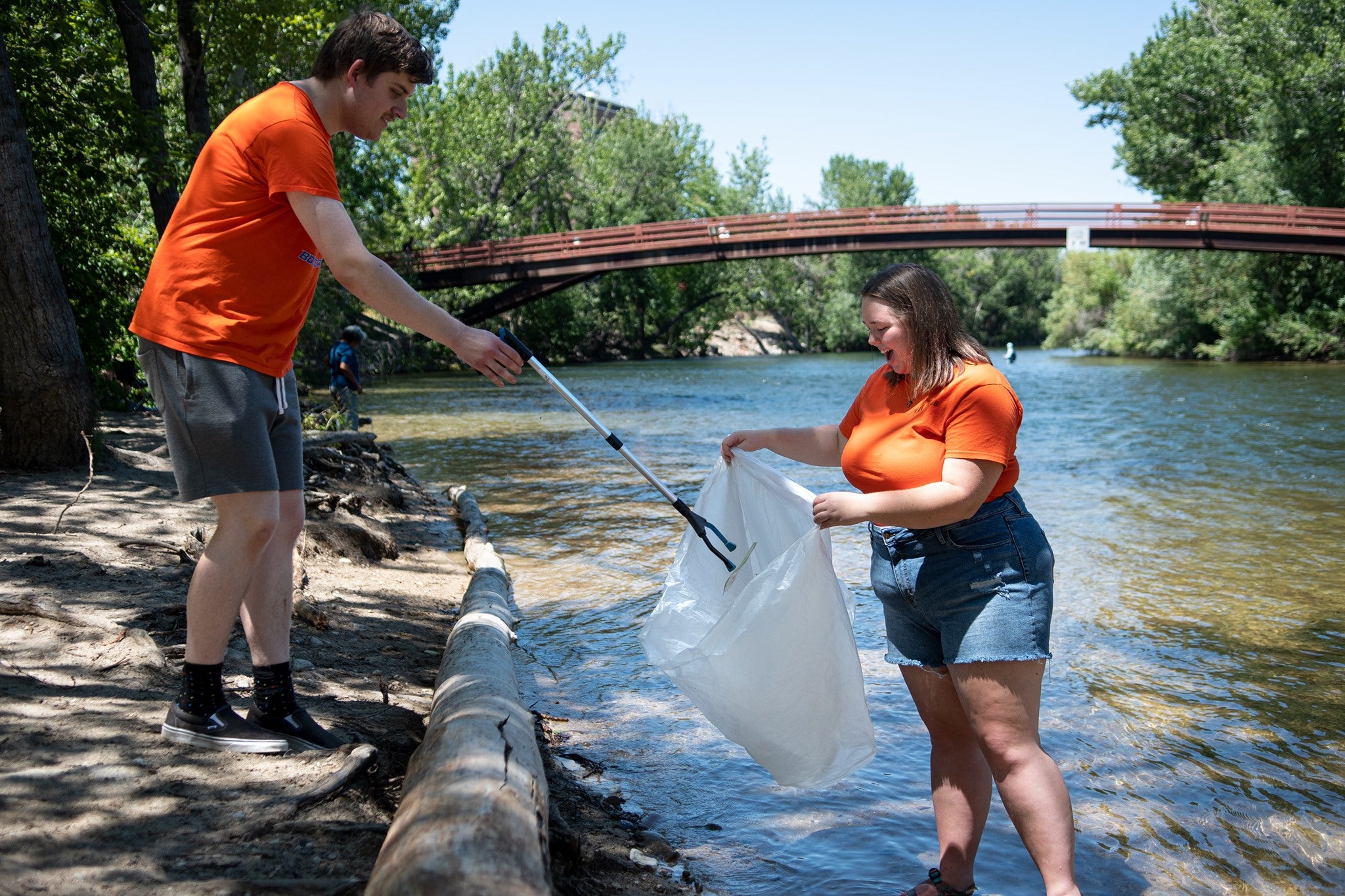 Two students pick up litter around the Boise river