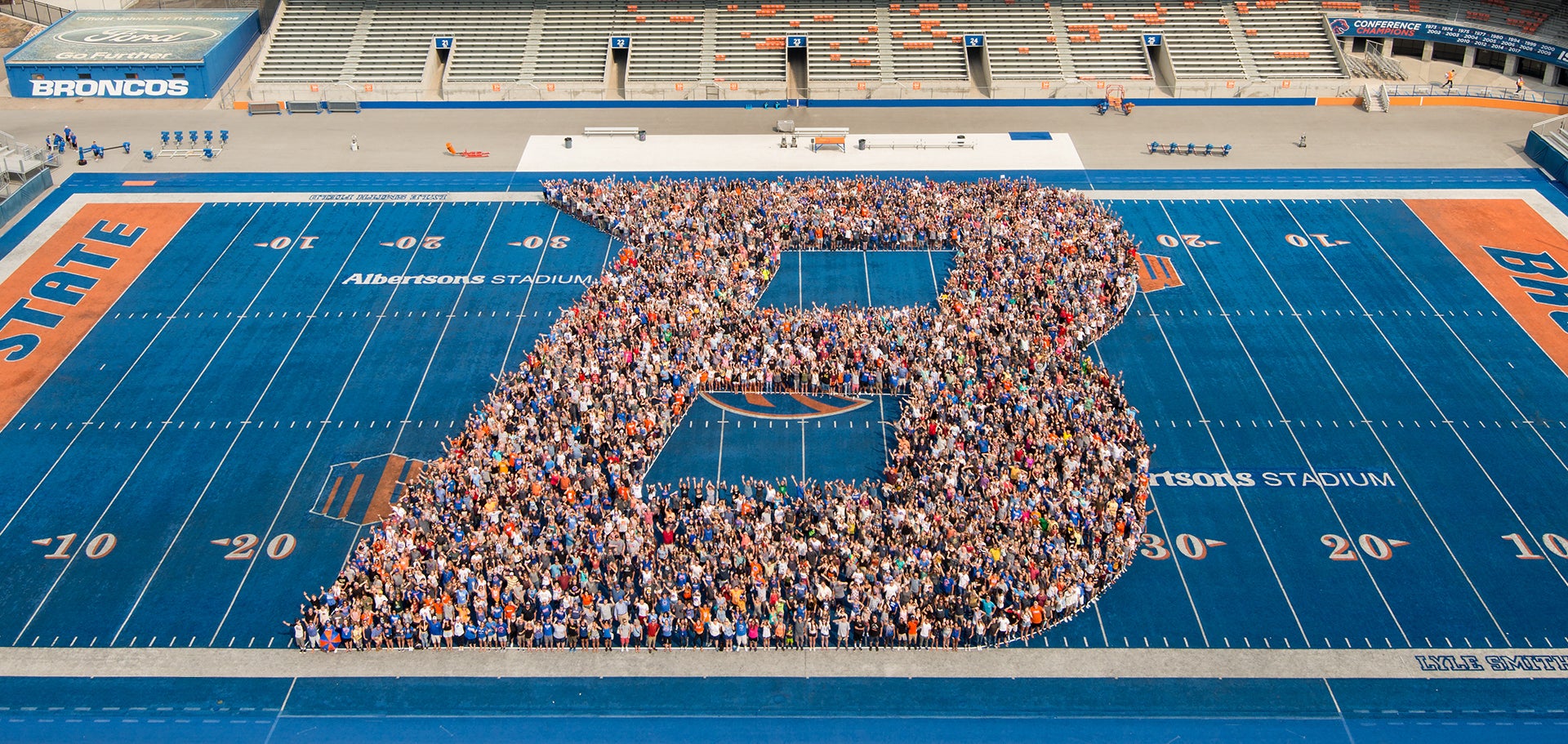Students form a B on the blue Football field