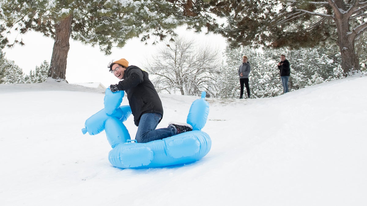 Students use inner tube to sled on snow hill
