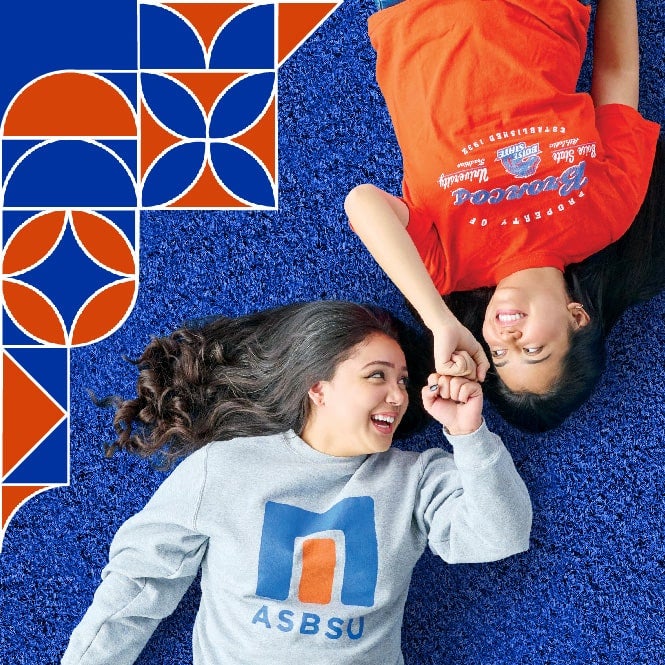 Two students laying down on the blue turf
