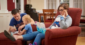 Online student works on a laptop with her family.