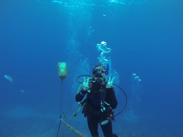 woman holds up two peace signs while scuba diving