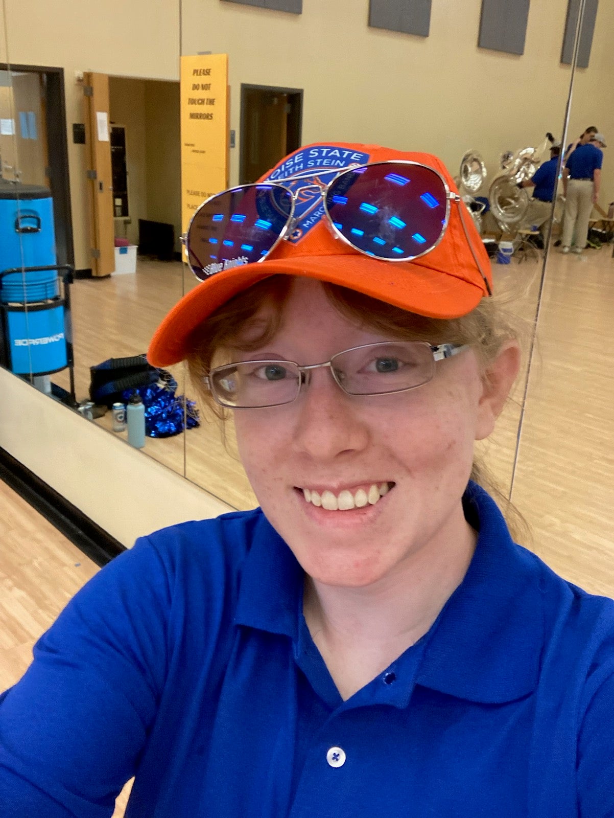Mackenzie Bennett wearing an orange hat and blue polo shirt standing in front of musical instruments