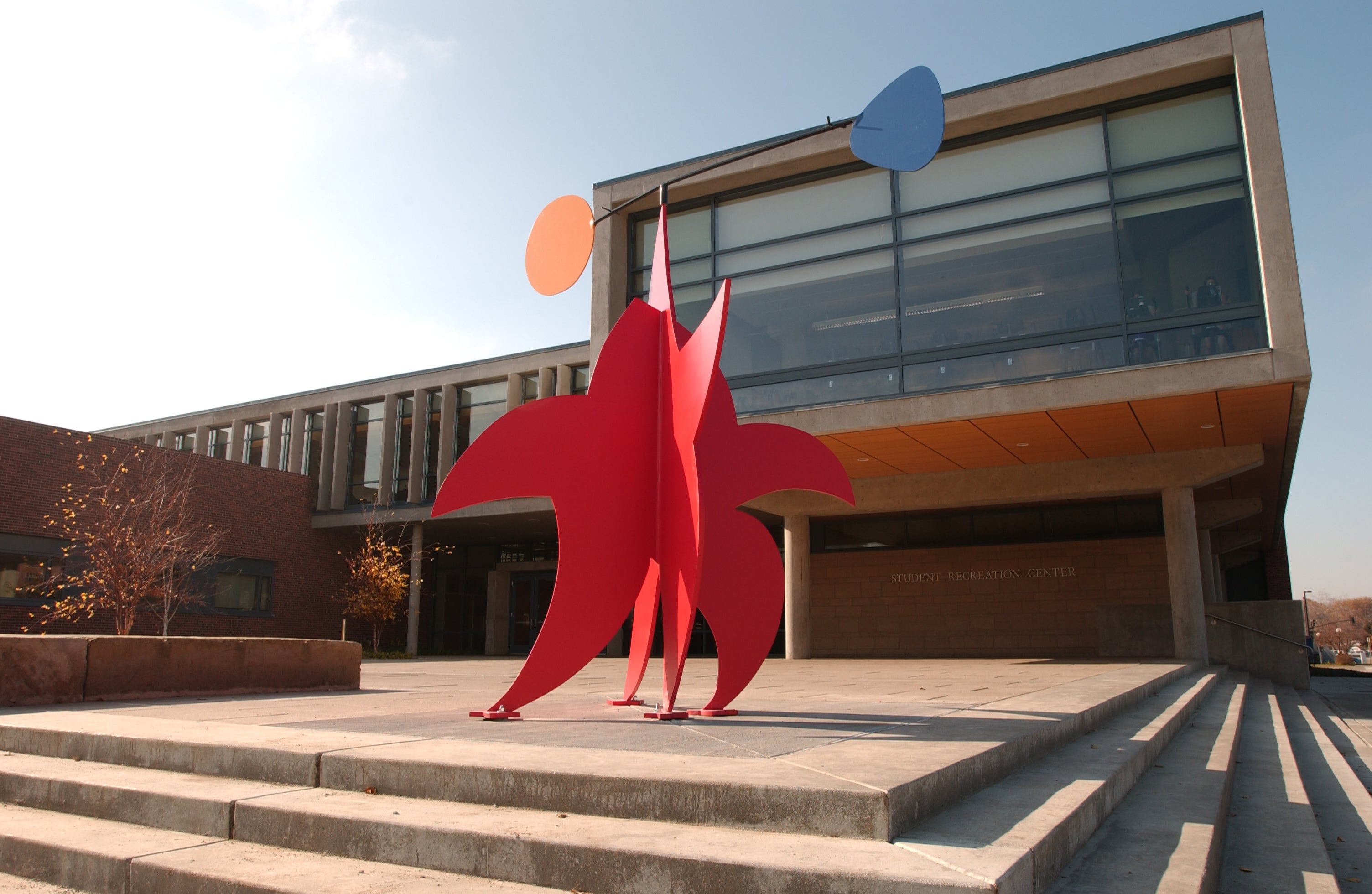 Red sculpture in the shape of a star with orange and blue shapes balancing on top of it.