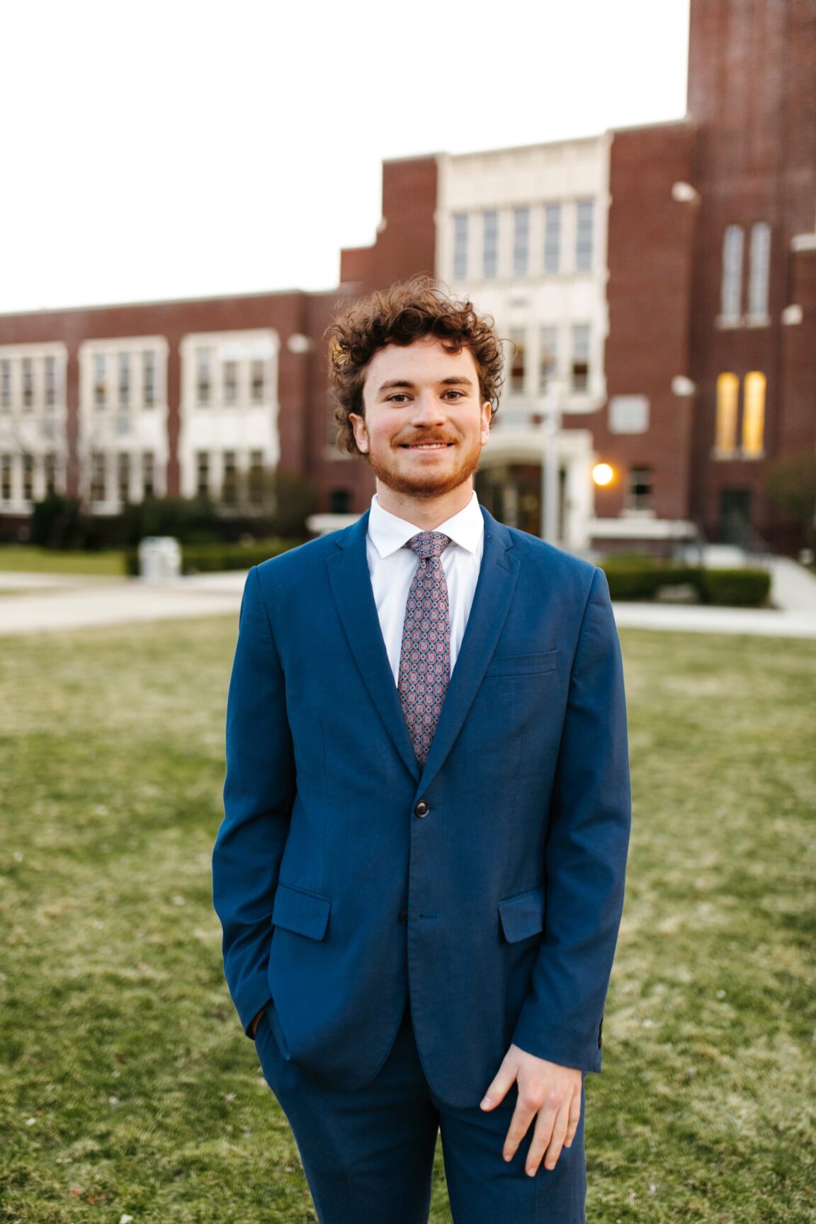 James Stringham standing in front of a brick building, smiling