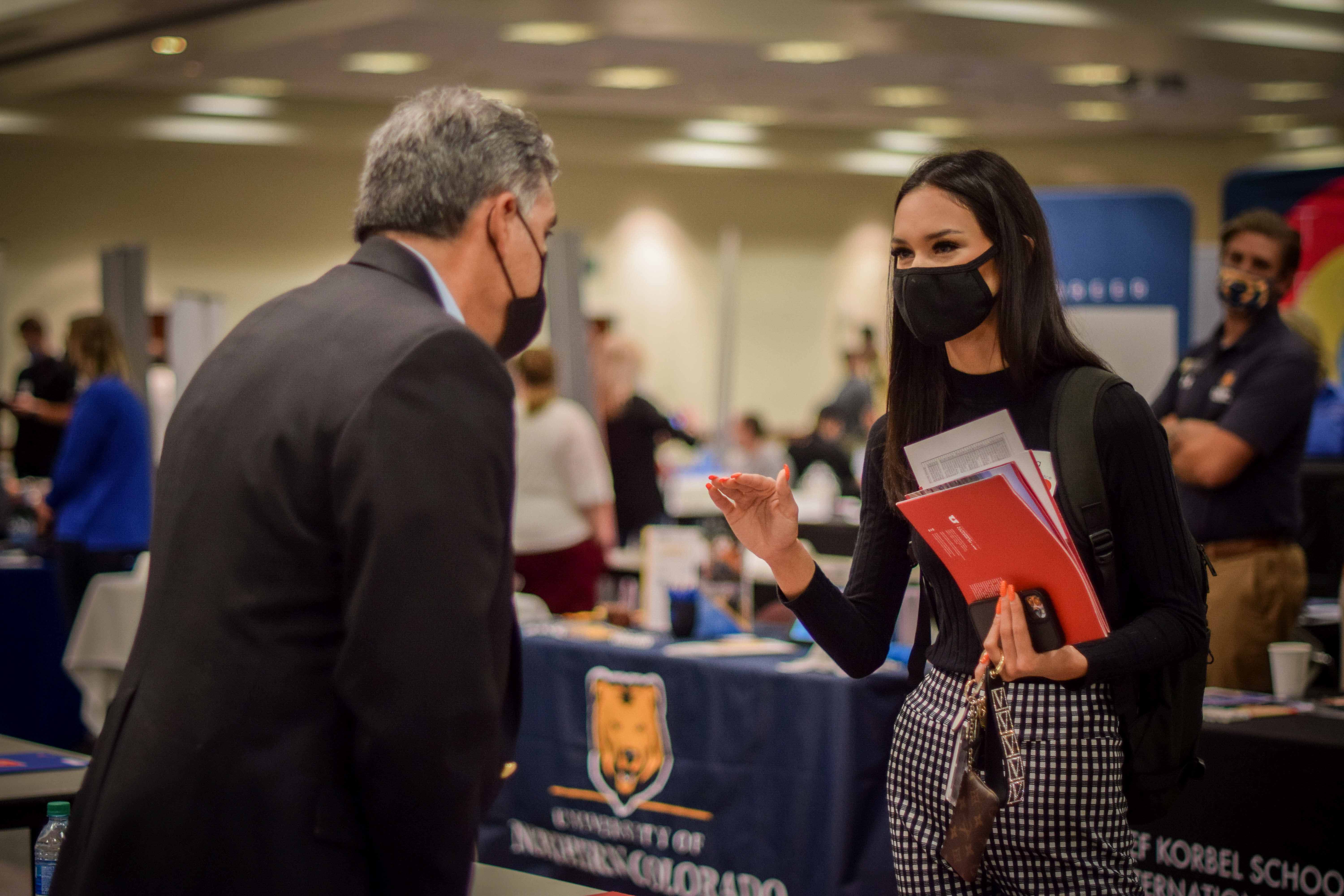 Masked student talking to an employer at the career fair