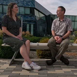 Photo of Owen McDougal sitting on a bench outside with a Channel 7 interviewer