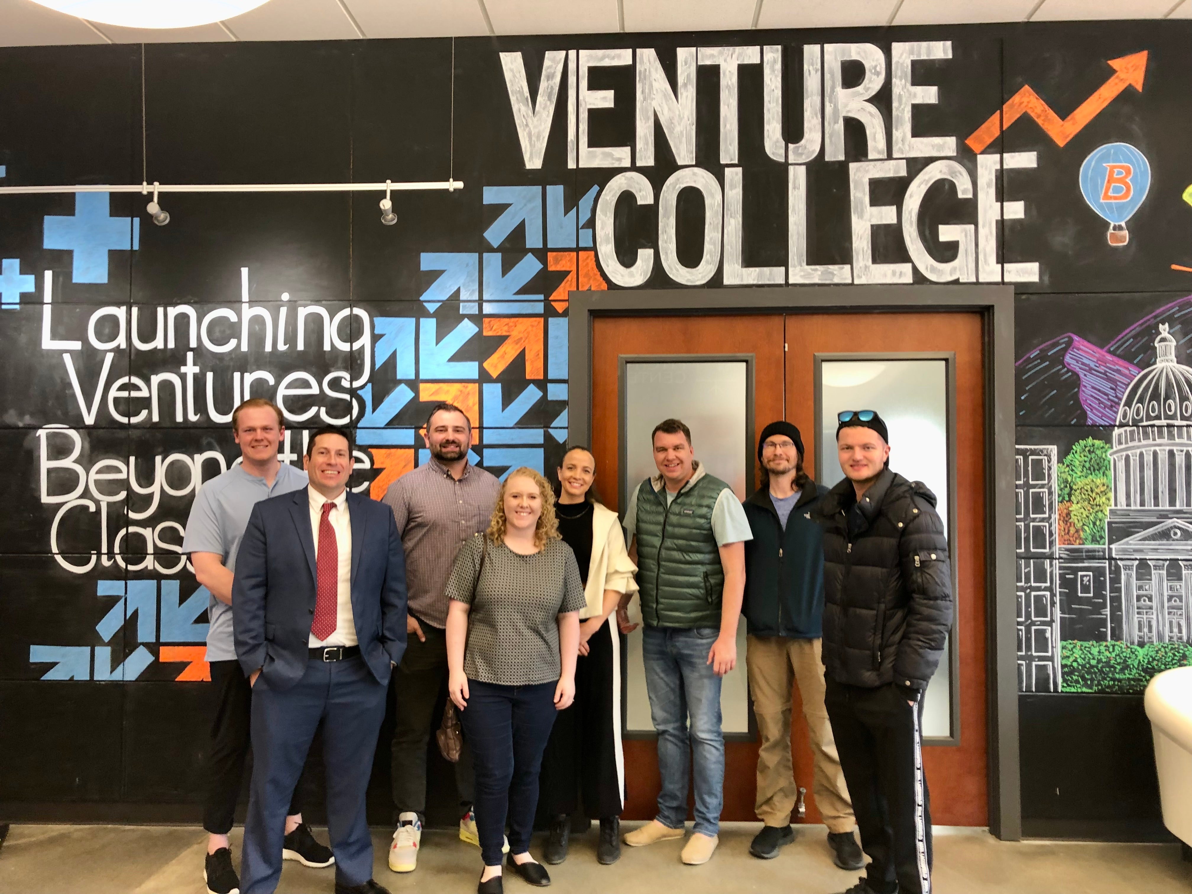 A group of Venture College Incubator participants stand in front of the Venture College mural in BoDo.