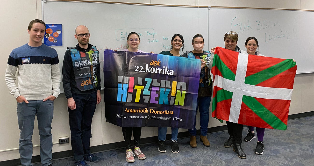Students and faculty with the Basque Studies program in a classroom on campus holding a banner that reads "Korrika 2022" and Basque Country flags