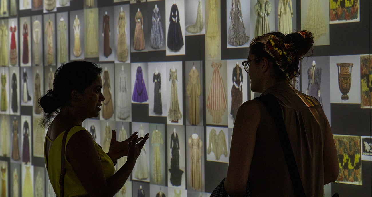 Two faculty in the College of Arts and Sciences talking about an exhibit of theatre costumes in the Stein Luminary digital museum