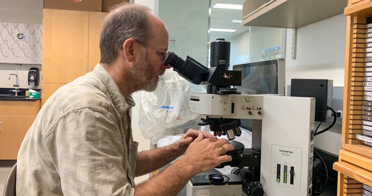 Matt Kohn, Boise State Geosciences professor, looking at thin slices of minerals using a petrographic microscope