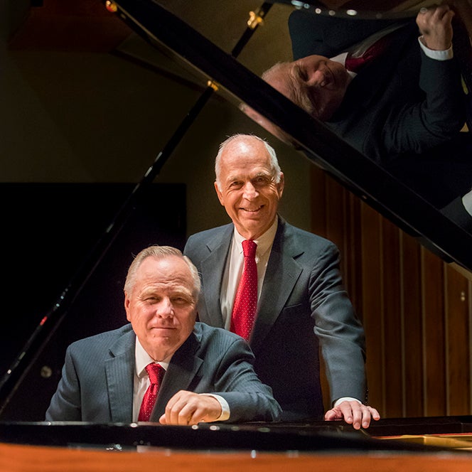 The American Piano Duo, Del Parkinson and Jeffrey Shumway, pose at a grand piano