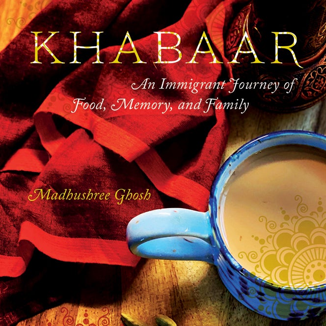 A cup of tea next to a brightly colored towel and stylized text that reads, "Khabaar: Khabaar: An Immigrant Journey of Food, Memory and Family by Madhushree Ghosh"