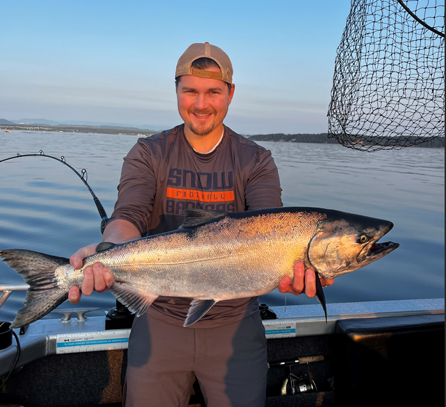 Kyle Gleed holding a fish on a fishing boat
