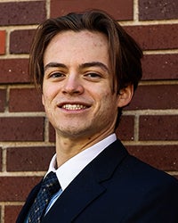 Picture of sales club officer Bazamir Urban against a brick wall.