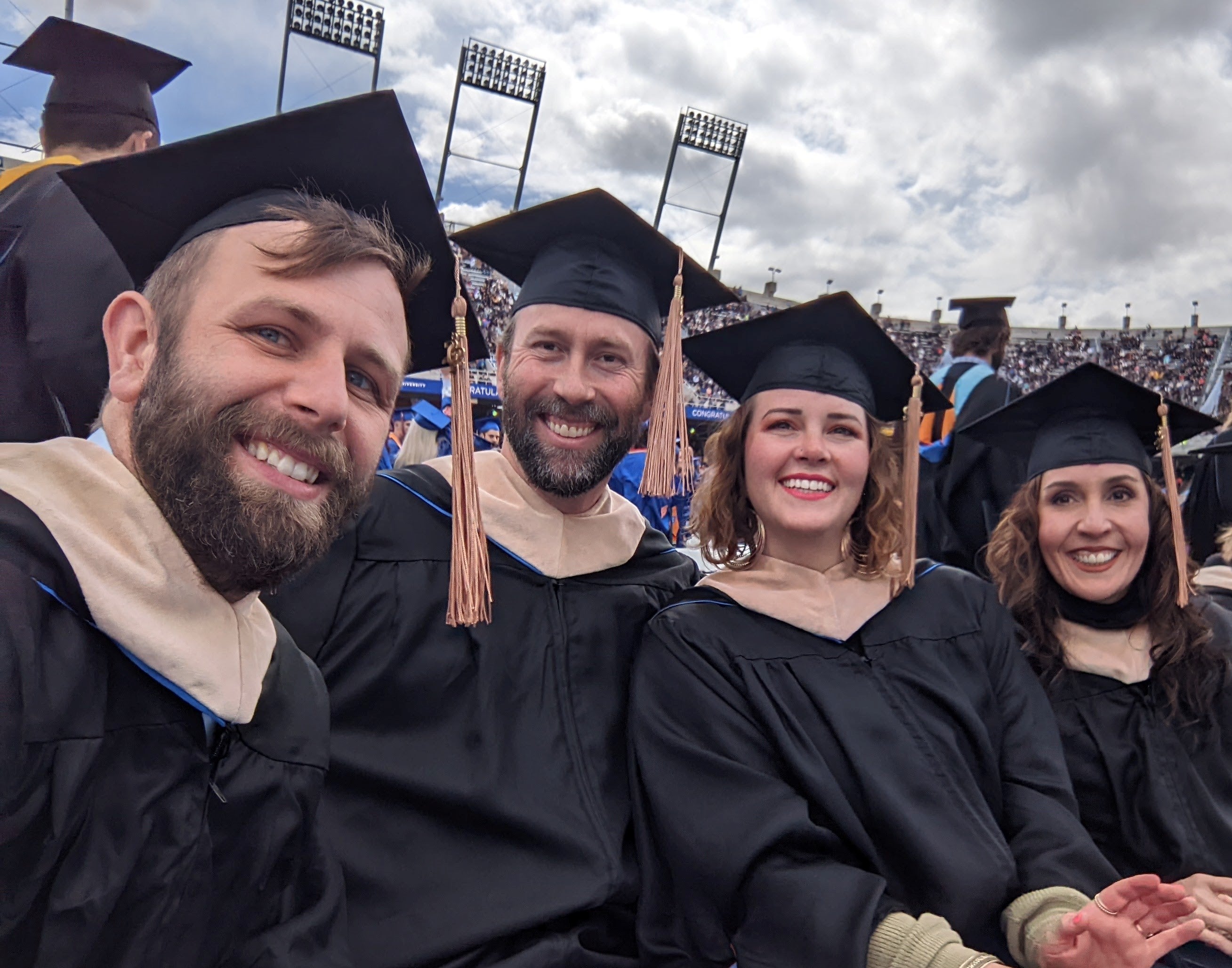 Four students take a selfie at the commencement ceremony at Bronco Stadium