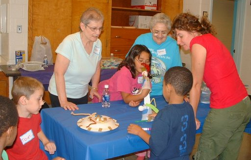 photo of kids and adults standing around a table