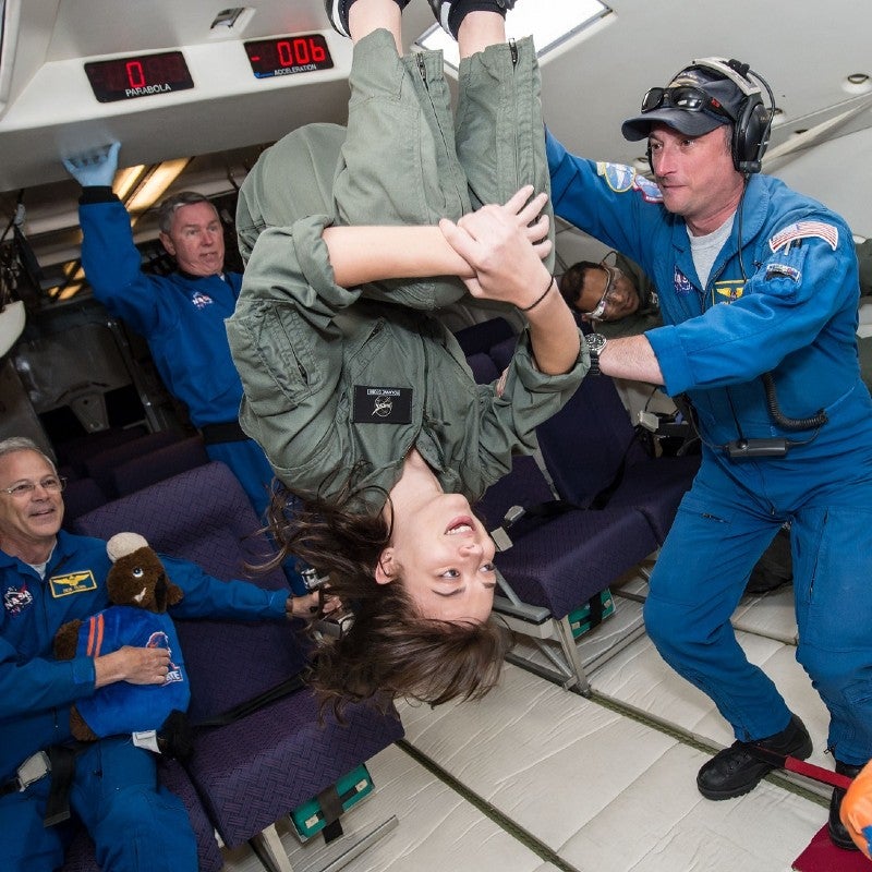 a female student floating upside down in a zero gravity flight