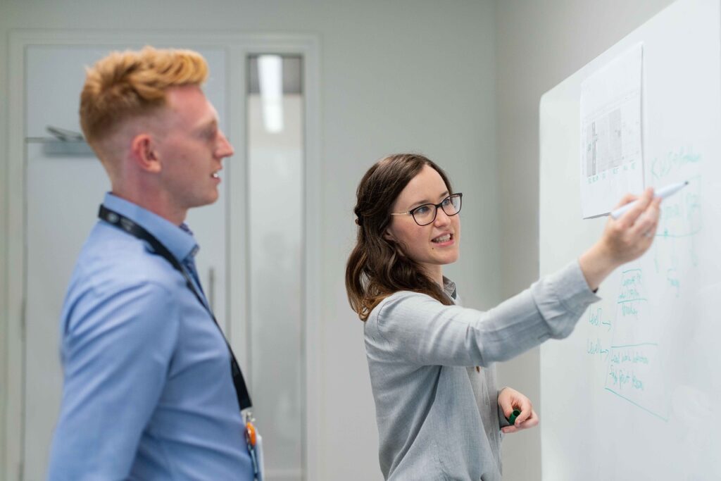 Two students working on a whiteboard project