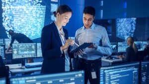 Two people working on computer code. 
