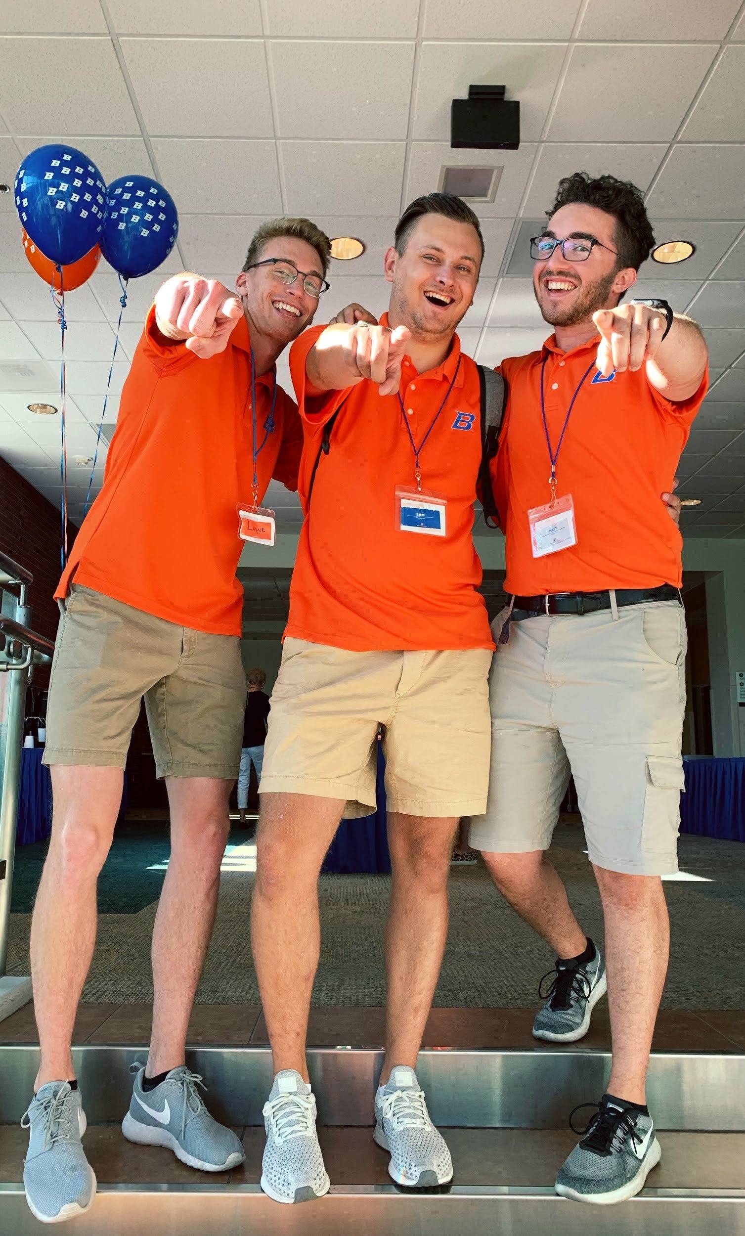 Three orientation leaders point at the camera 