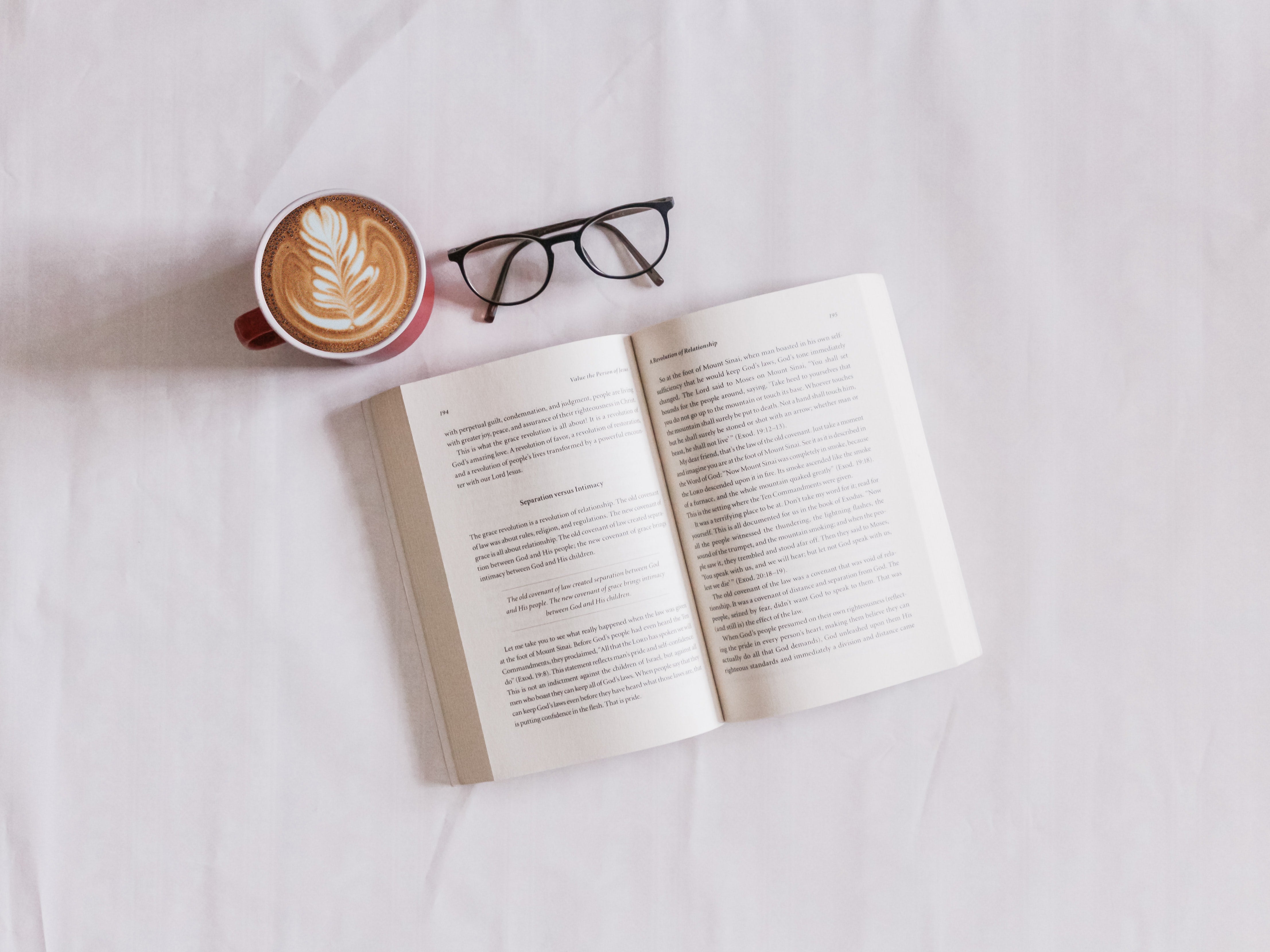 Book, coffee mug, and glasses lie on table 