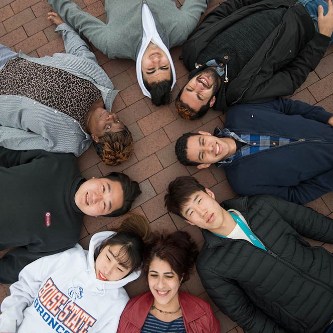 Students lie in a circle and smile for an overhead photo