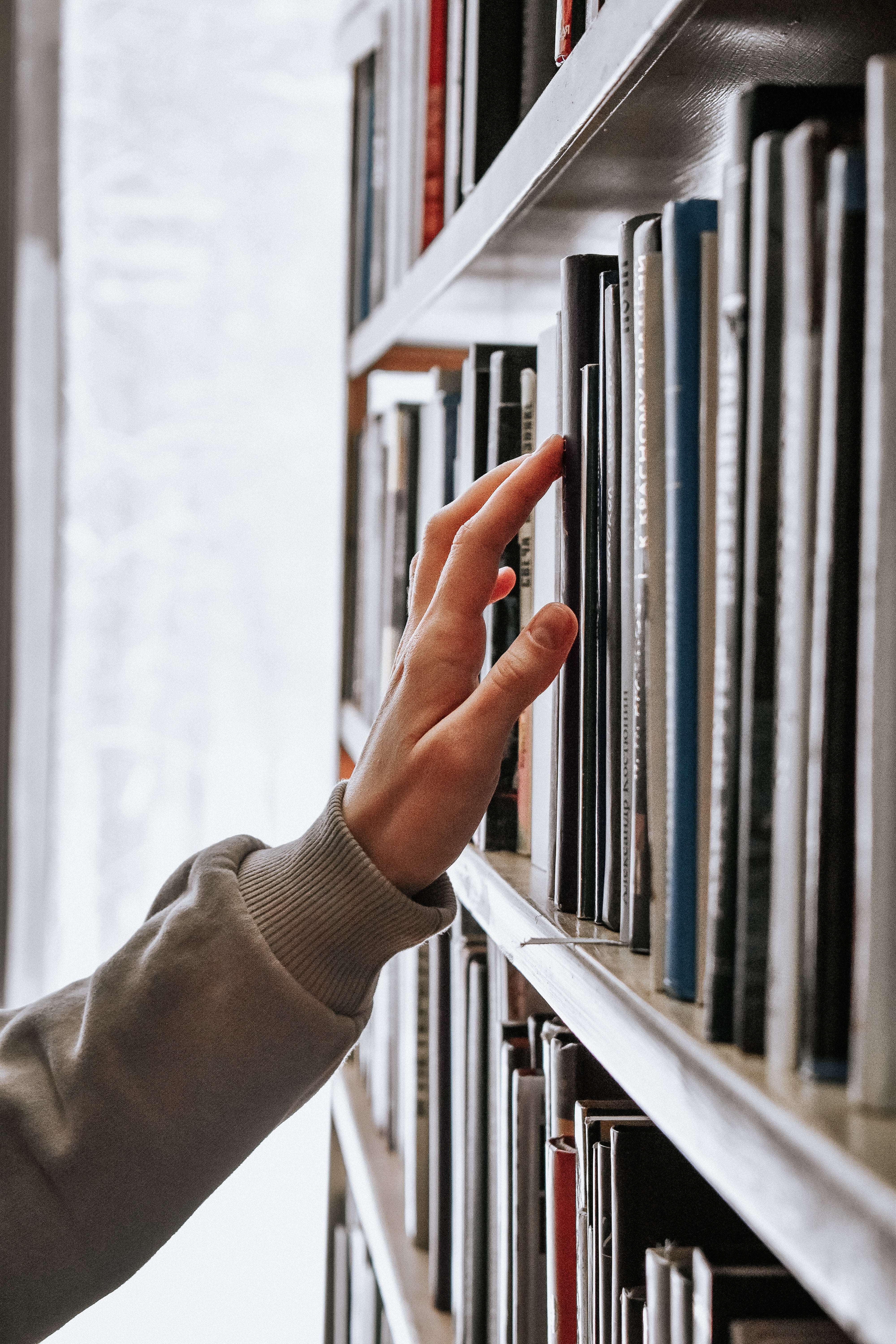 Hand touches library books on shelf 