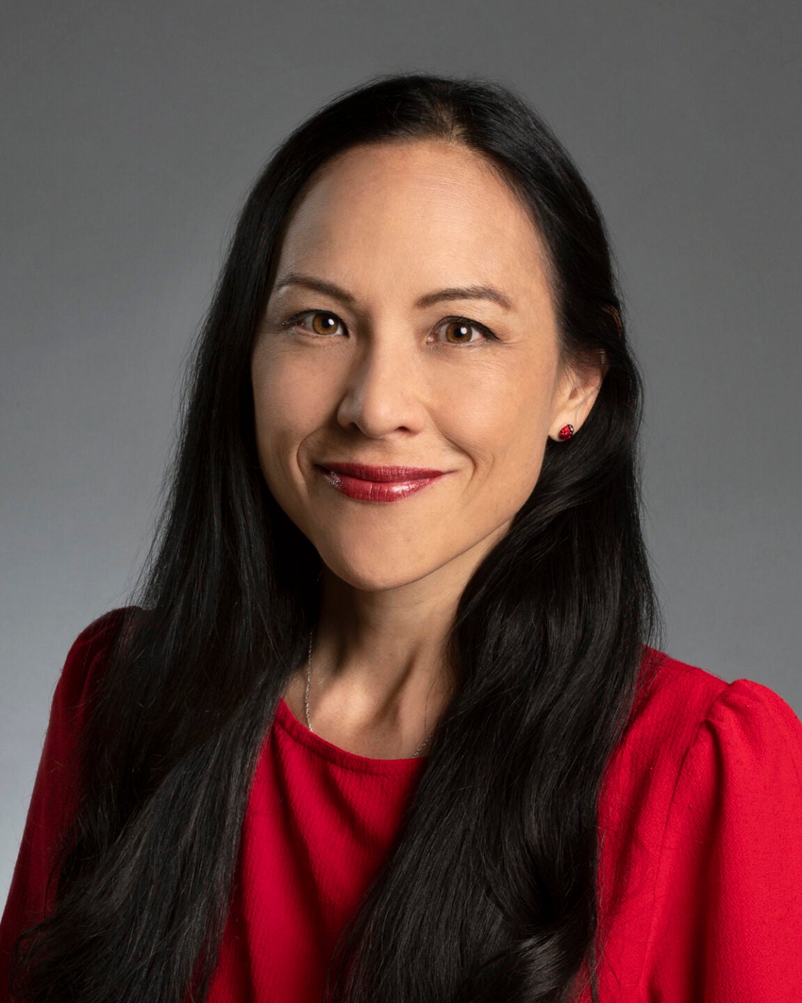 Portrait of Margaret Sass with her hair down, wearing a red top.