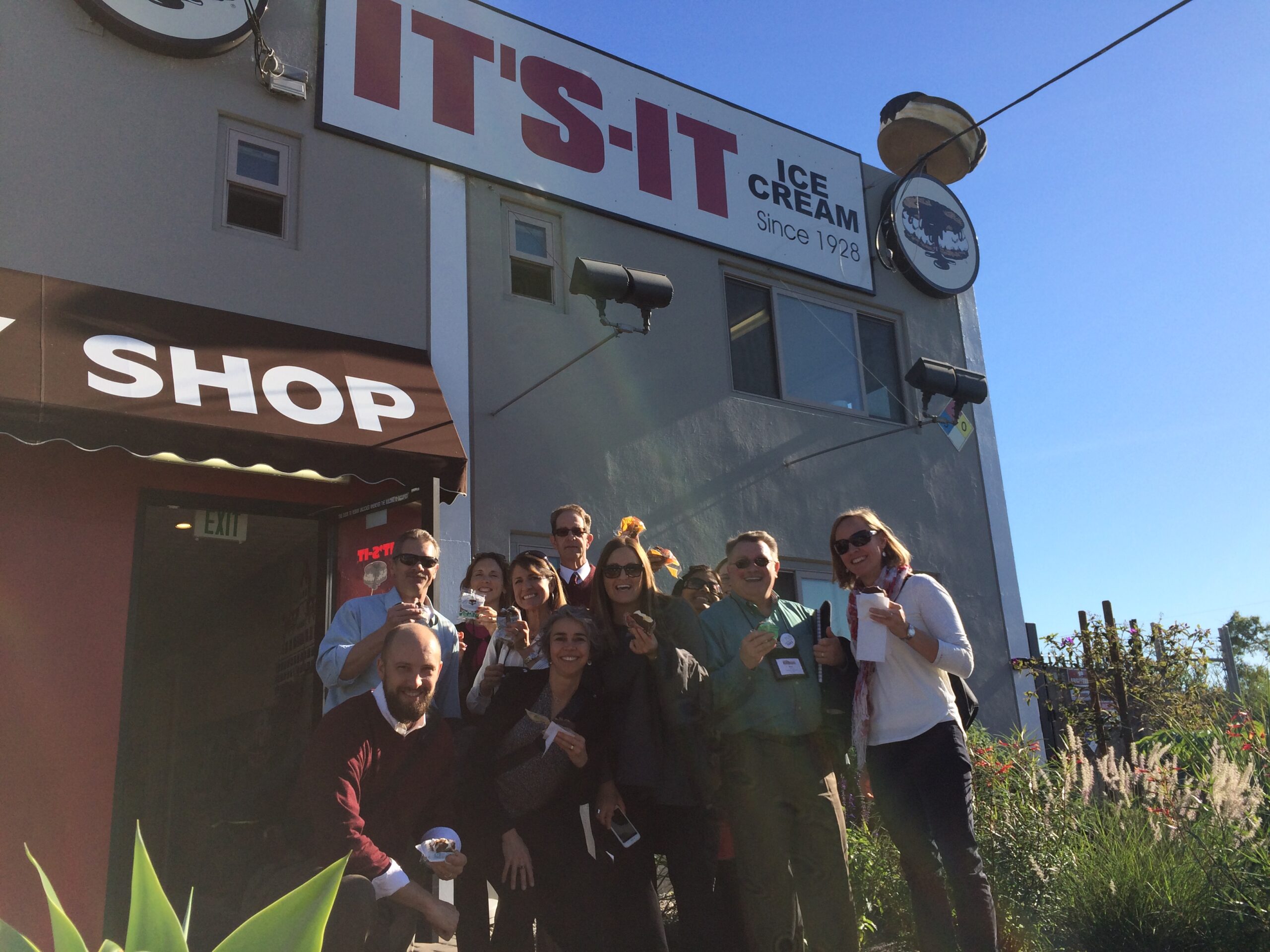 A group of faculty smile for the camera in front of an ice cream store.