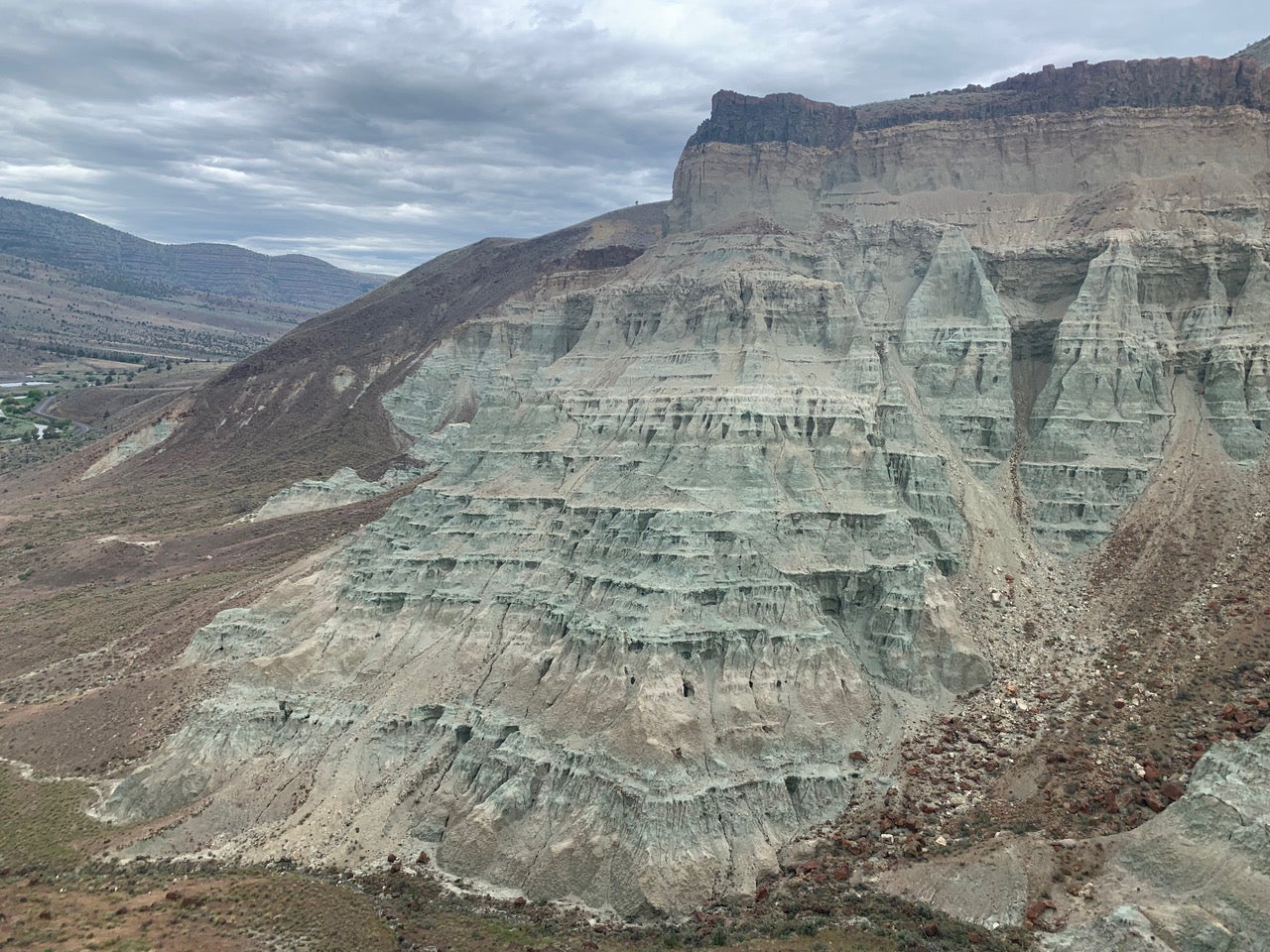 A hill with many soil layers tinted green. 