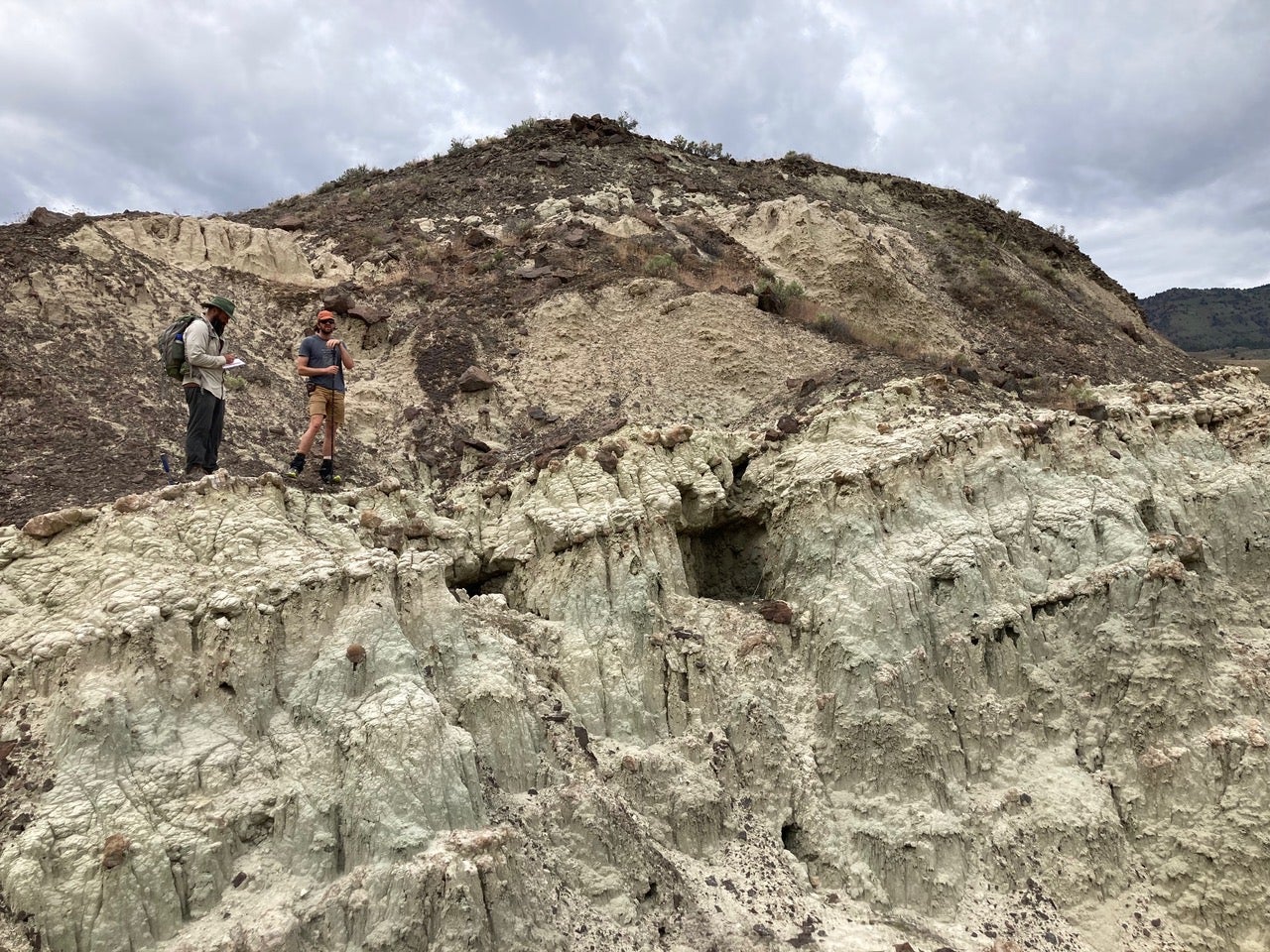 Two researchers stand atop a hill. 