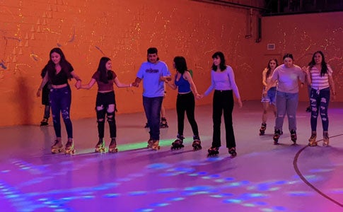 Photo of a group of TRIO Upward Bound students holding hands while roller skating