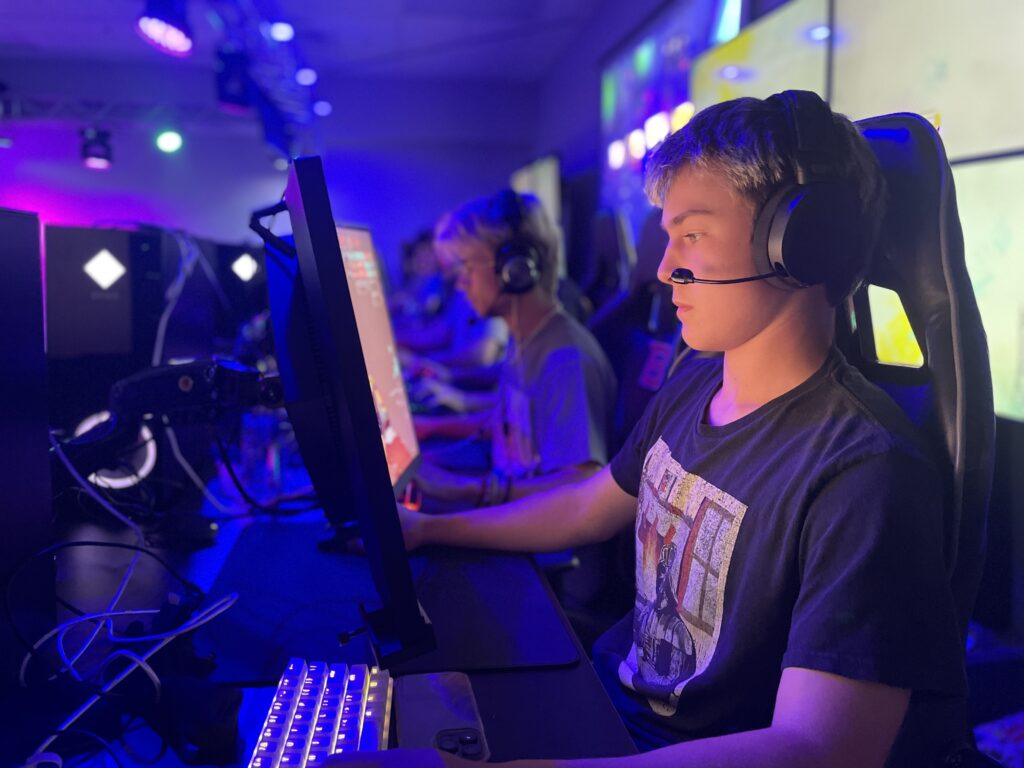 Photo of Wyatt Morrison sitting at a gaming station playing a video game in the Boise State Esports Arena.