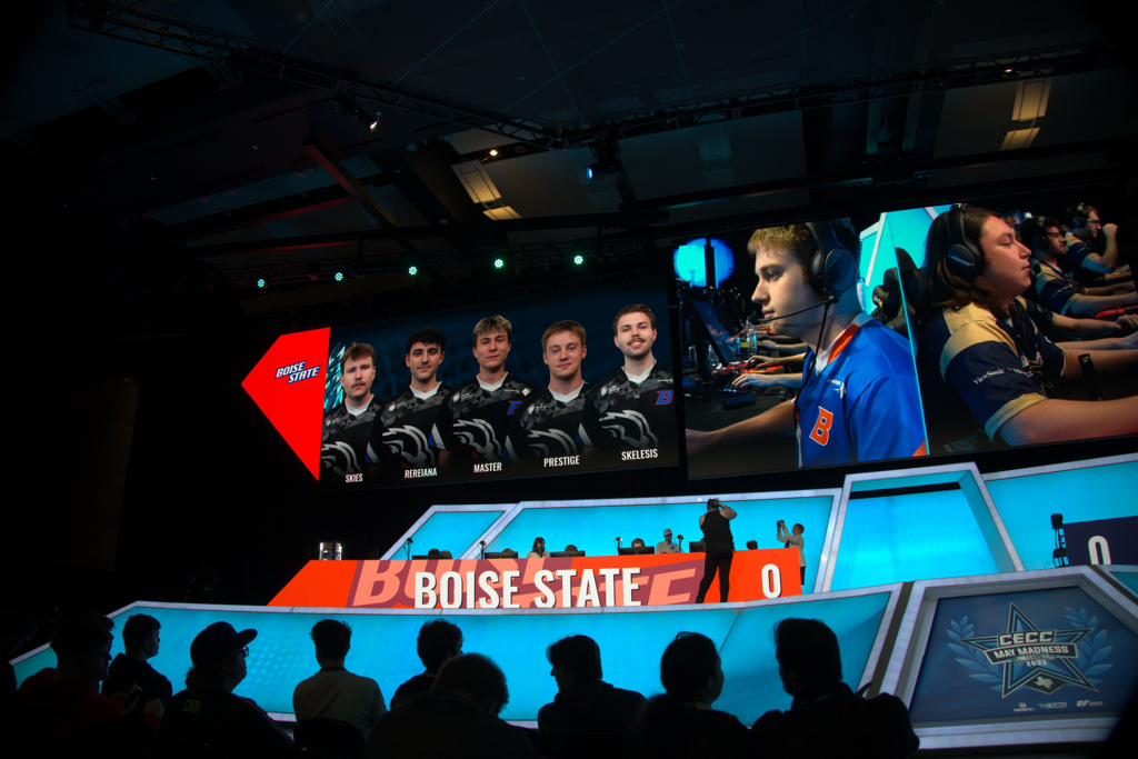 Photo of a group of students competing onstage in a large, modern esports arena.