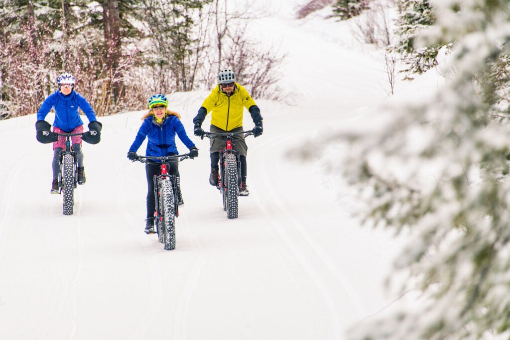 Three people riding bikes in the snow