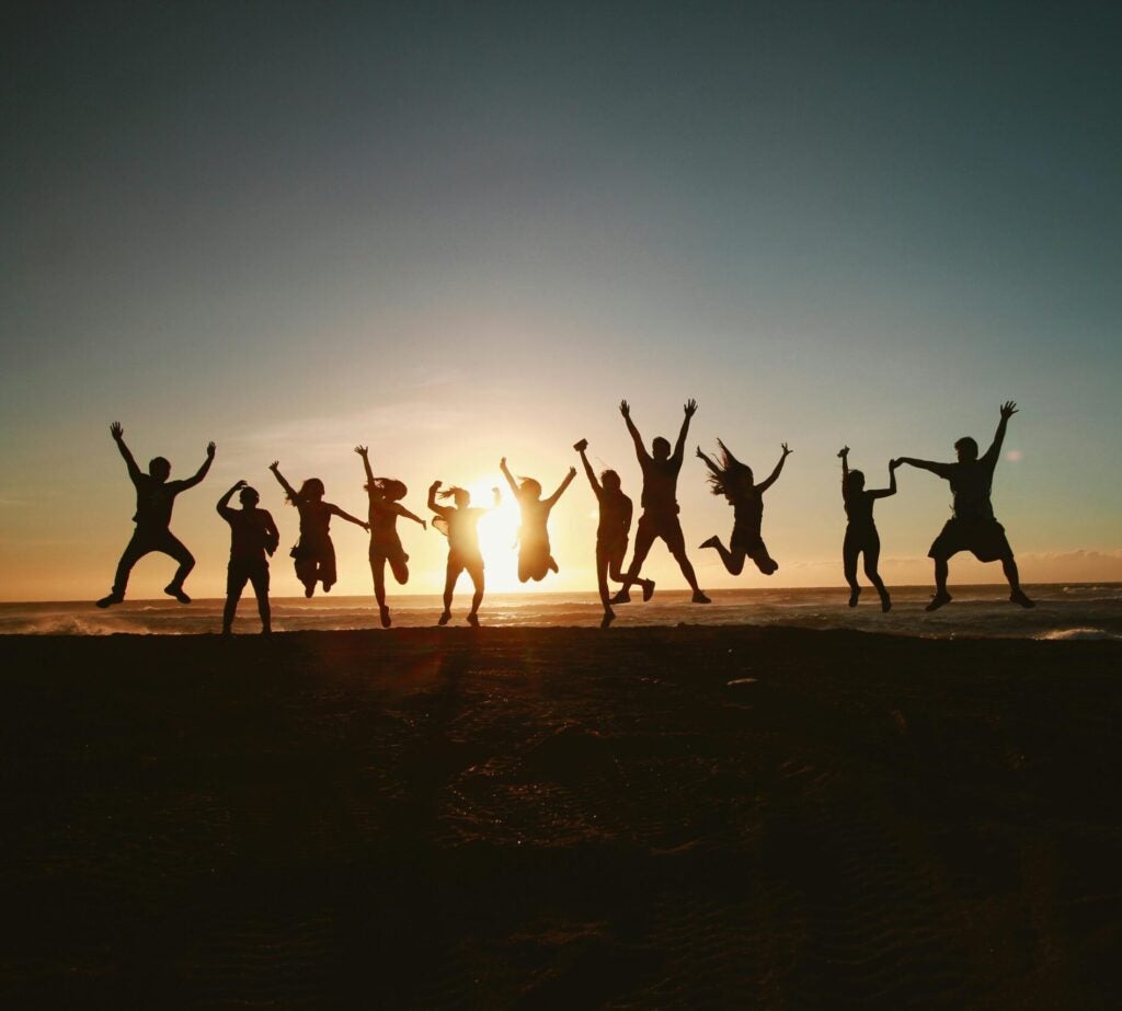 people jumping by the ocean at dawn.