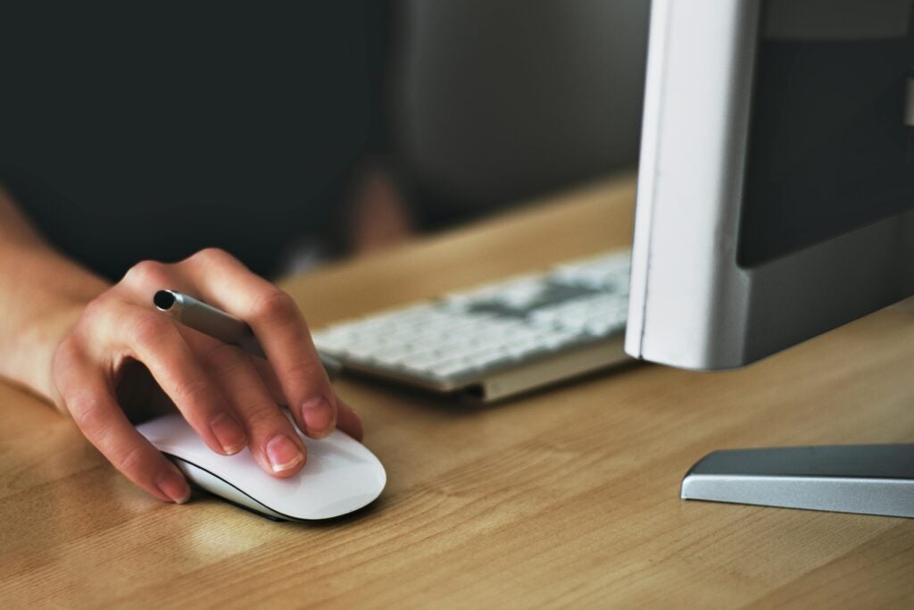 Hand using computer mouse on a wooden desk