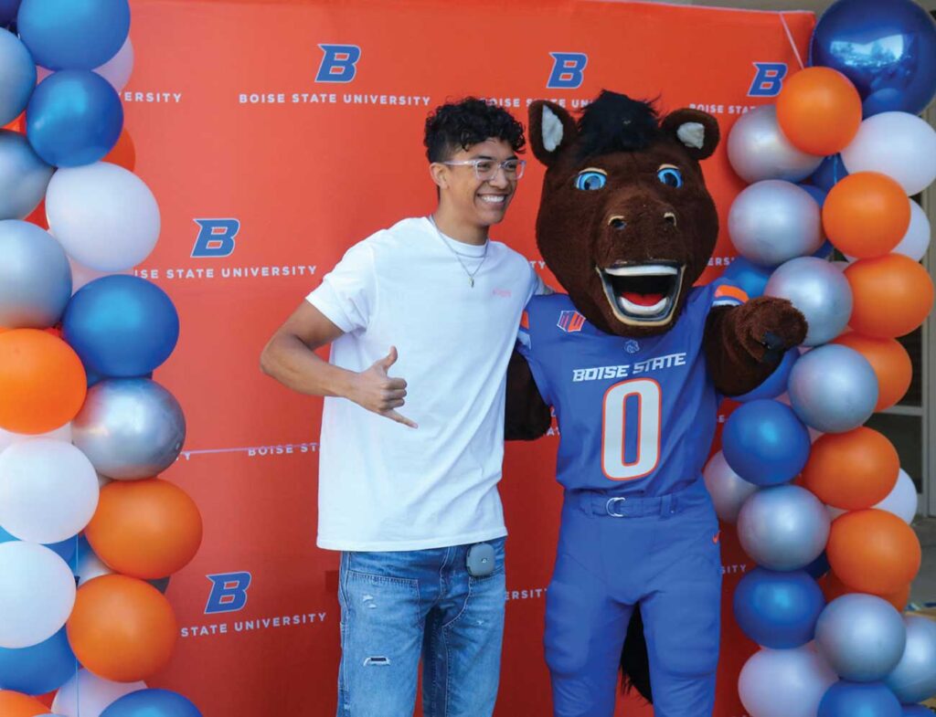 Student "hangs ten" while posing with Buster Bronco at the photobooth at the 2024 BroncoWelcome Picnic