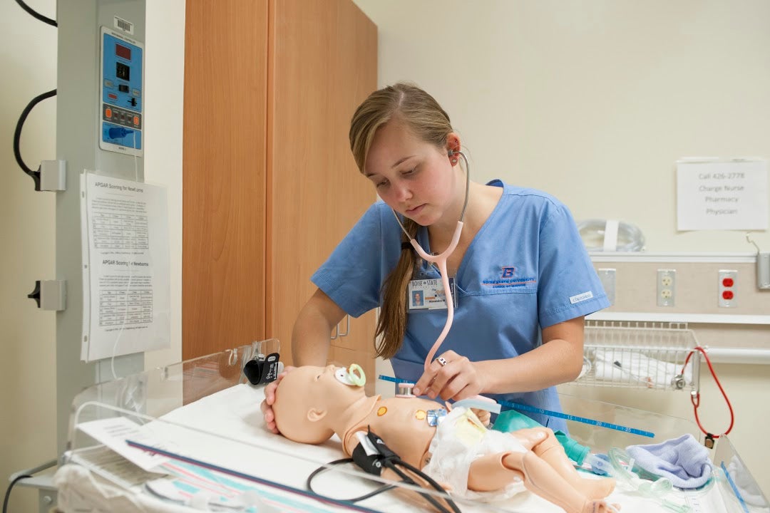Nursing student practicing on baby high fidelity manikin