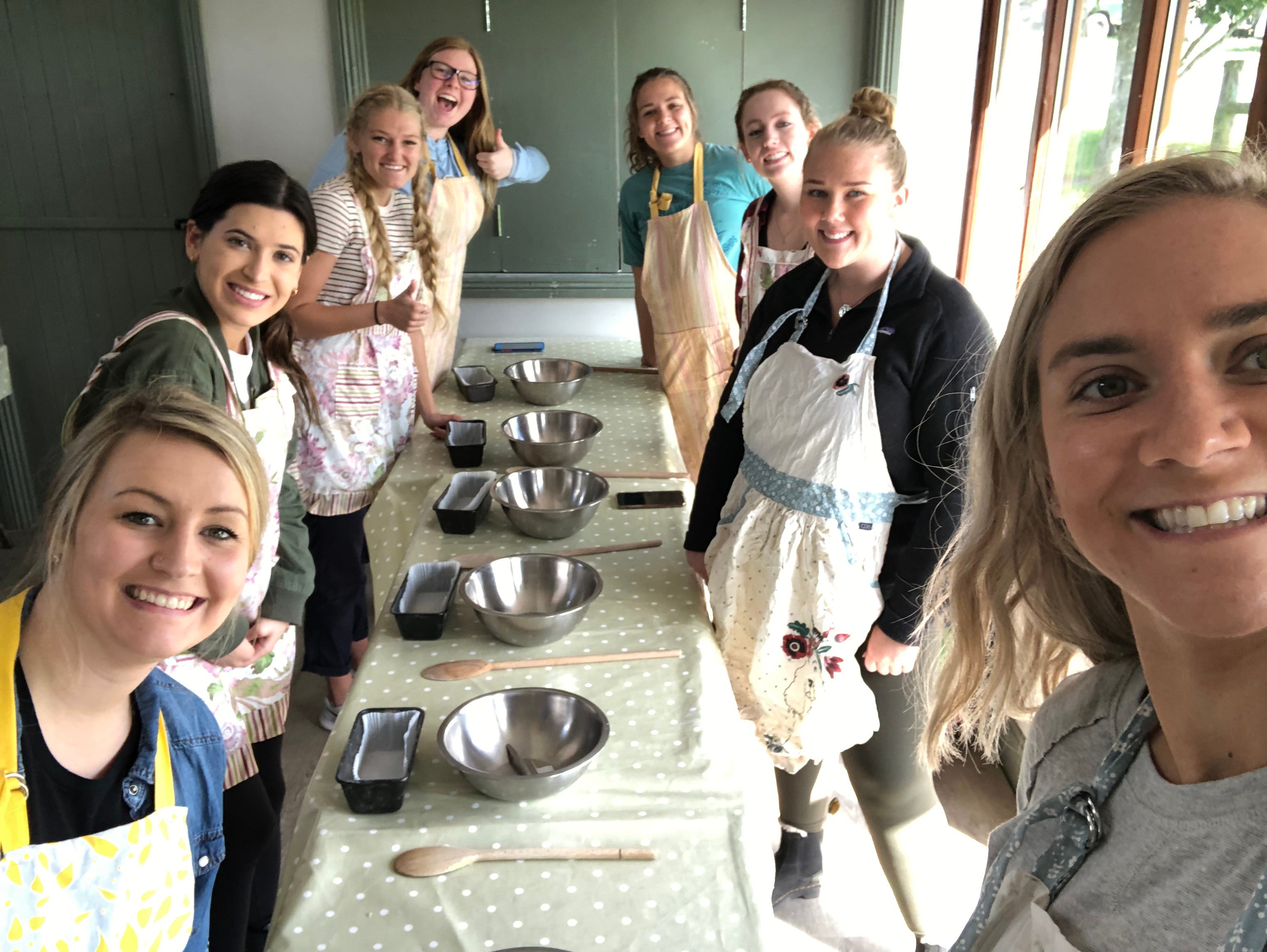 Students posing next to a table while they learn how to make bread 