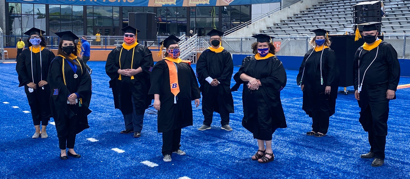 First graduating class of the Master of Science in Respiratory Care program pose in regalia on the Blue Turf