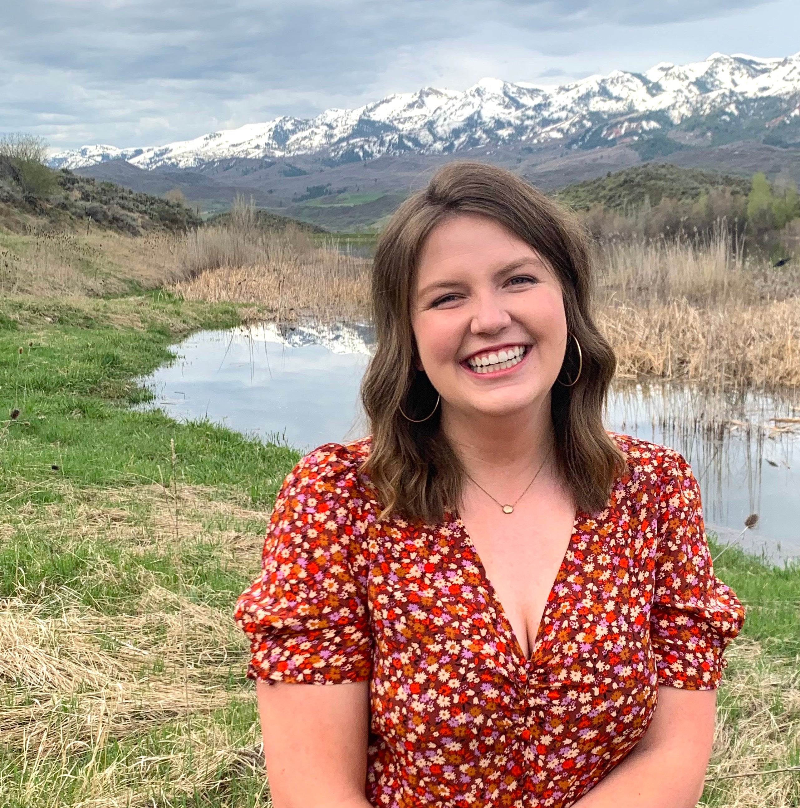 Madison Sullivan poses for a photo in front of a stream and mountains. 
