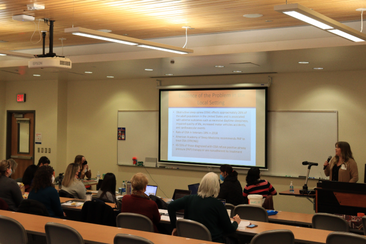 Doctoral students present their final projects during a spring in-person session.