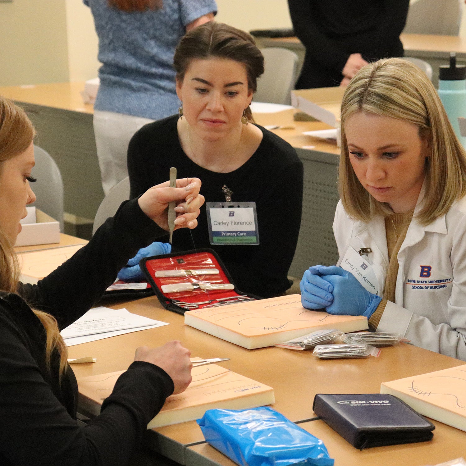 Two nurse practitioner students watch a suturing demonstration.
