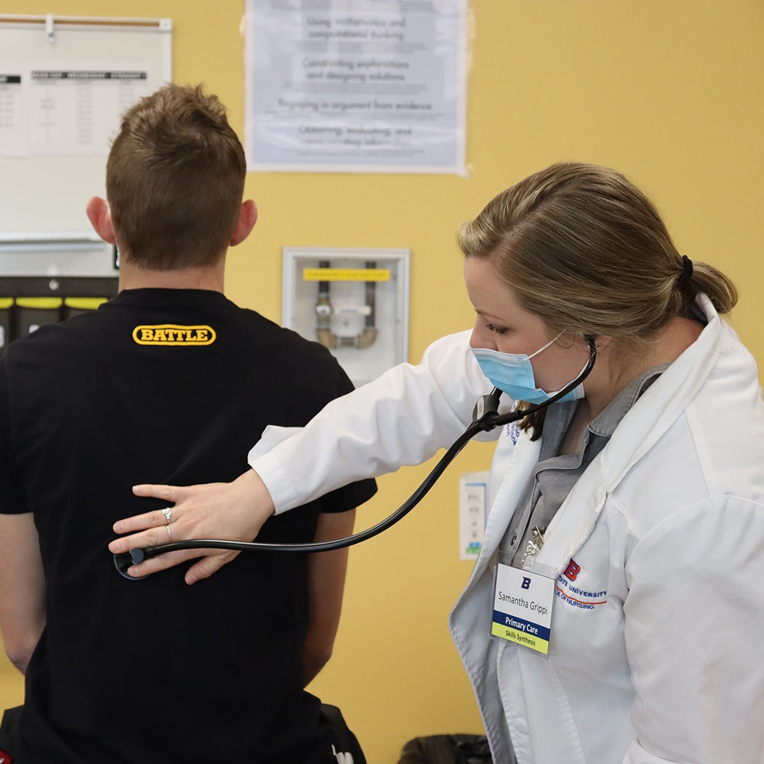 A nurse practitioner student uses a stethoscope to listen to a patient's breathing.
