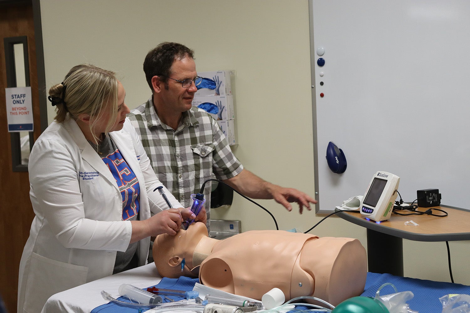 A nurse practitioner student practices intubation on a manikin.