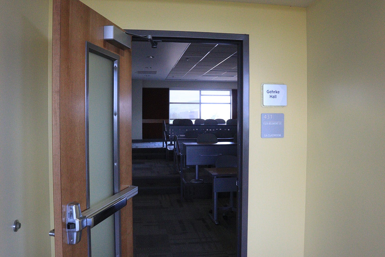 A plaque reads "Gehrke Hall" opposite an open door to into a lecture hall.