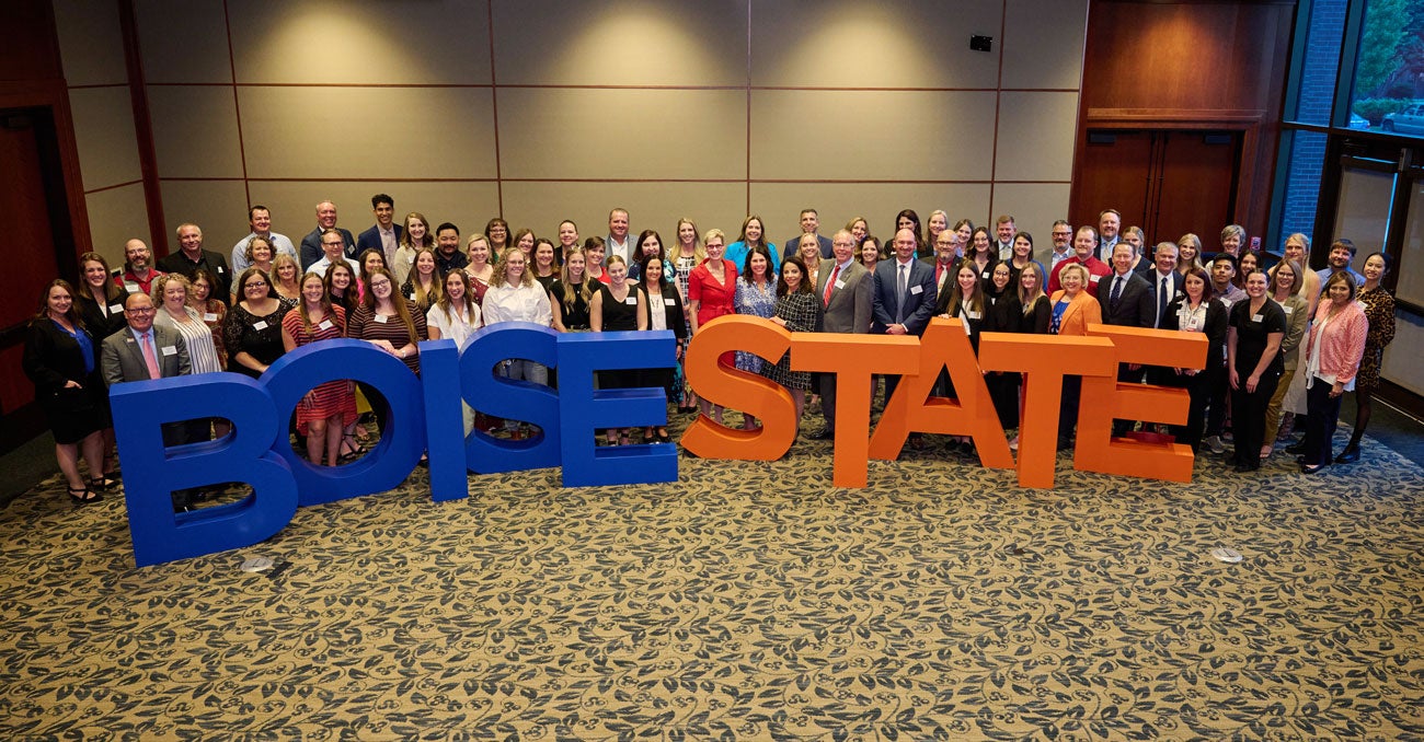 A crowd of people stand behind four foot tall letters that spell out Boise State.